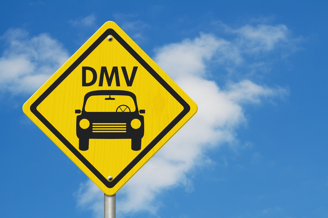 Visit to the DMV Highway Warning Sign, Icon of a car and text DMV on a yellow highway sign with sky background